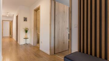 Un couloir doté d’un plancher en bois, d’un banc et d’une porte ornée de panneaux de bois verticaux.