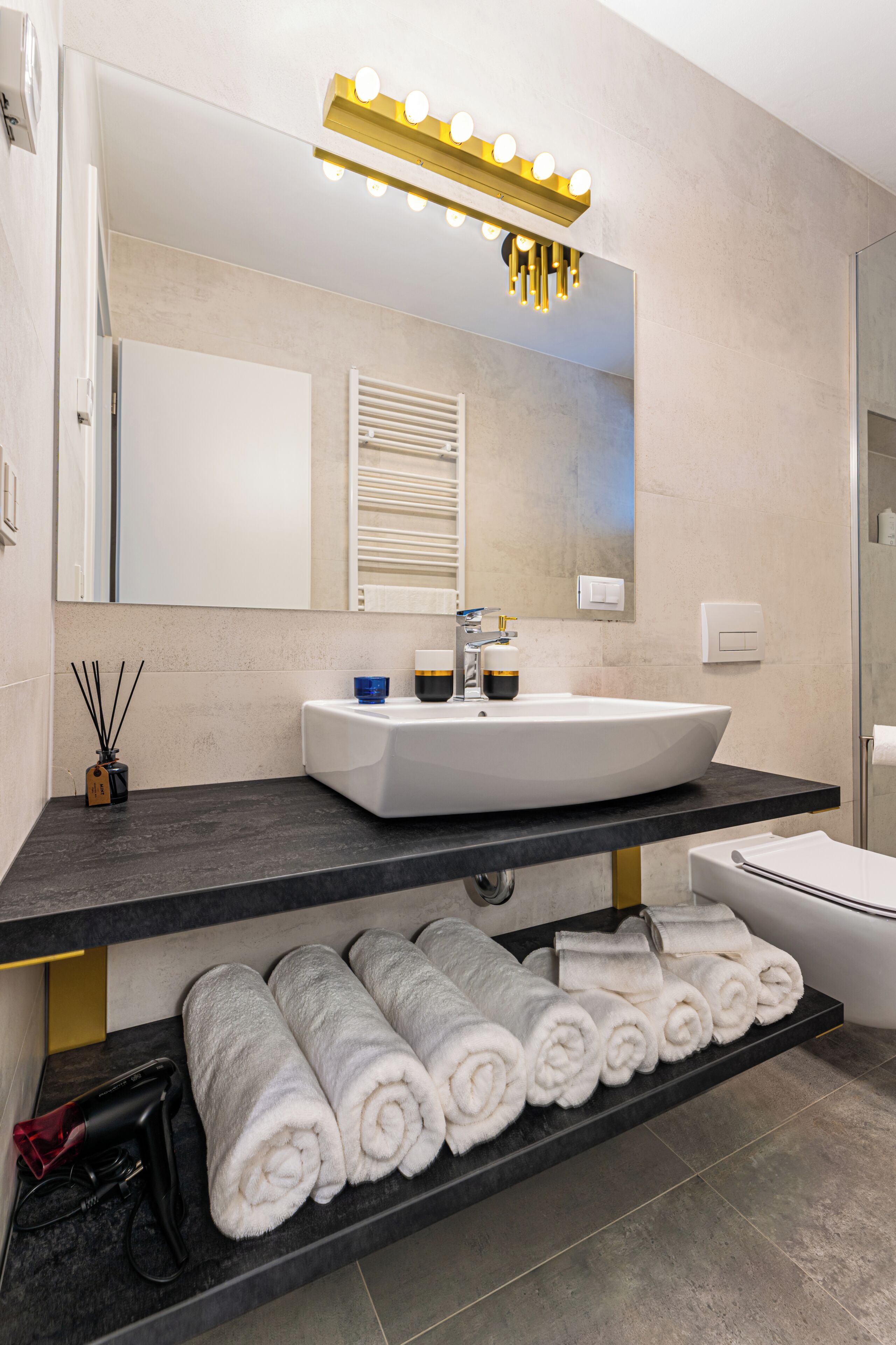 A modern bathroom with a large mirror, vanity, and a towel rack.