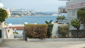 Zona de piscina con vistas al mar y una colina al fondo.