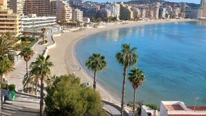 Un paisaje urbano costero con una playa extensa, palmeras y varios edificios, incluyendo hoteles y edificaciones residenciales.