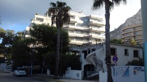 Un edificio de varios pisos con balcones, palmeras y una escalera que conduce a la entrada.