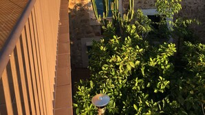 Un edificio in pietra tradizionale con tetti in tegole di terracotta, un cactus in primo piano e montagne sullo sfondo.