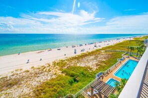 Un complexe hôtelier en bord de mer doté d’une piscine, de parasols et offrant une vue dégagée sur l’océan.