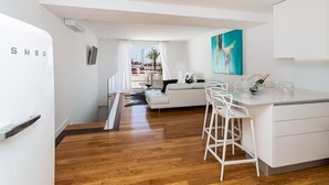 Cocina moderna con muebles blancos, una barra con taburetes y vistas a un puerto deportivo por la ventana.