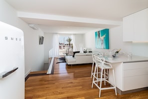 A modern kitchen with white cabinetry, a bar area with stools, and a view of a marina through the window.