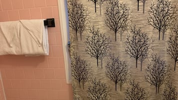 A bathroom with a tiled floor, a bathtub, a toilet, and a shower curtain with a tree pattern.