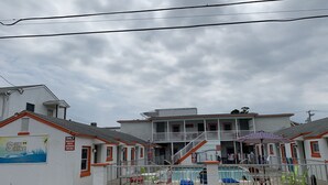 A hotel with a covered outdoor area, a pool, and a sign indicating guest-only access. - SunShine Motel (Wildwood)