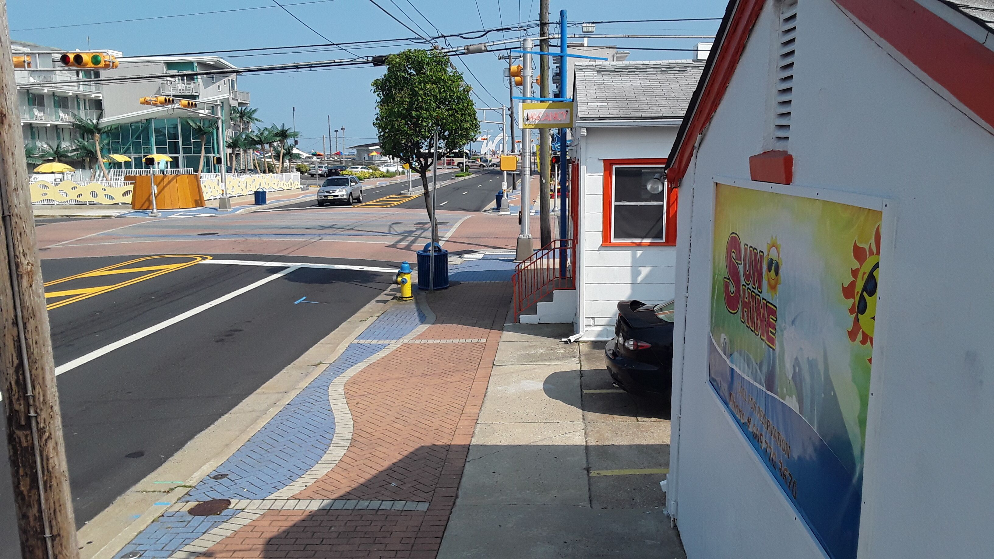 A street view with a white building featuring a colorful mural on the right.