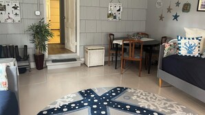 A cozy living room with a dining area, a large starfish-patterned rug, and a potted plant. - Beach Melody, Long Beach WA (Long Beach)