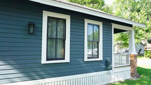 A house with a porch, a brick chimney, and a small garden area. - Historic Bungalow! 2bed, 2bath, 2den, Downtown Humble, IAH 8min! (Humble)