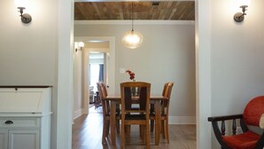 A dining area with a wooden table and chairs, a hanging light fixture, and a white cabinet. - Historic Bungalow! 2bed, 2bath, 2den, Downtown Humble, IAH 8min! (Humble)