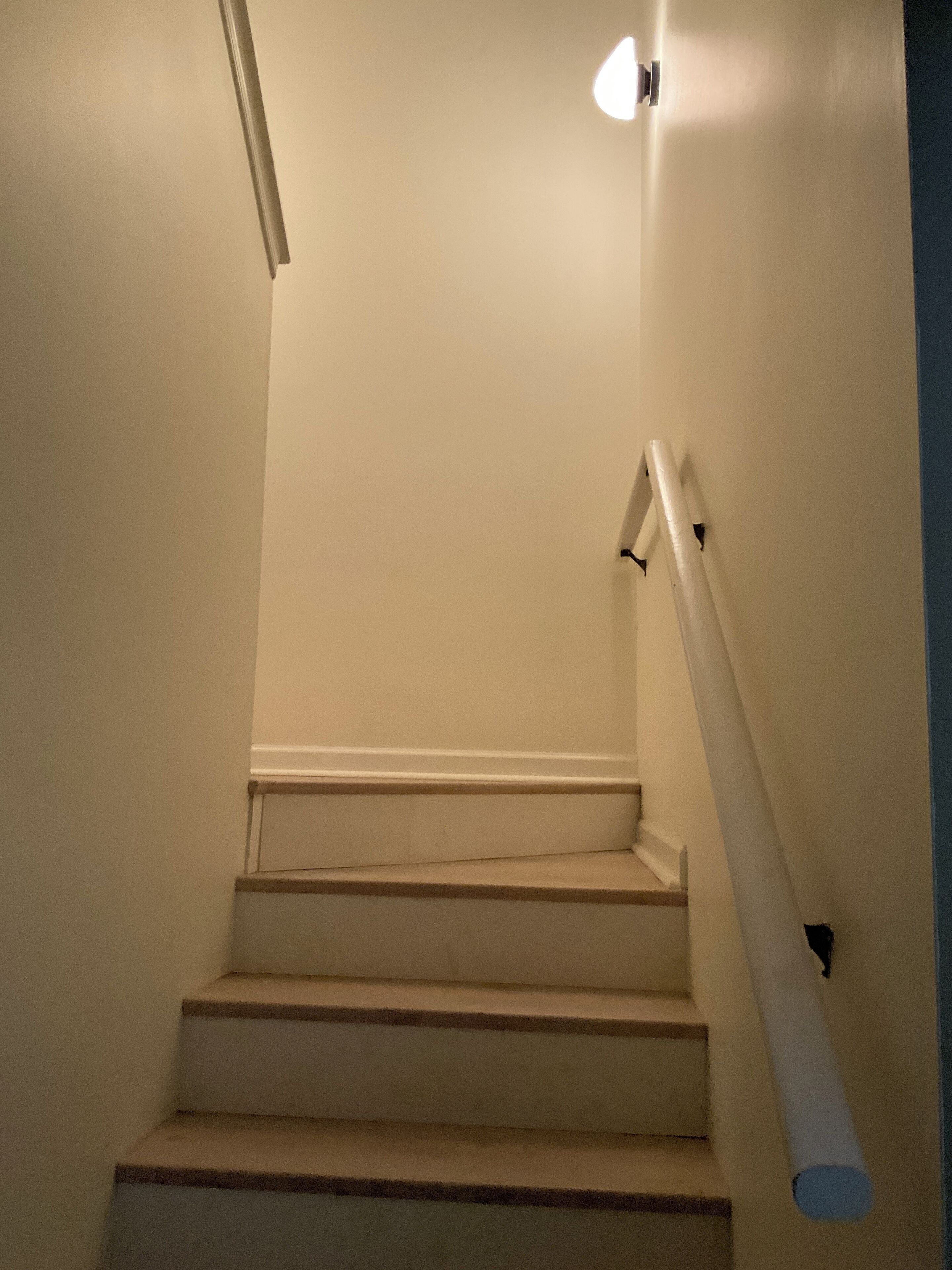 Eine Treppe mit Handlauf und Wandleuchte.