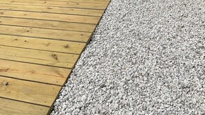 Une jetée en bois s’étendant sur une étendue d’eau, avec une clôture blanche et une maison en arrière-plan.