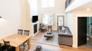A spacious living area with a fireplace, a sofa, a television, and a dining table with chairs. - Unique Silo Suite with Jacuzzi Tub, Kitchen, Fireplace, Living Room (Millersburg)