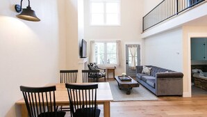 A spacious living area with a dining table, chairs, a sofa, and a TV mounted on the wall. - Unique Silo Suite with Jacuzzi Tub, Kitchen, Fireplace, Living Room (Millersburg)
