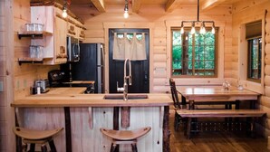 Ein Holzblockhaus-Interieur mit Küche, Essbereich und Barhocker.