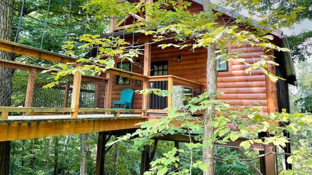 A wooden cabin with a balcony, surrounded by trees. - Luxury Treehouse Getaway with Treetop Views (Millersburg)