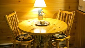 A wooden dining table with a lamp, surrounded by four chairs with floral cushions. - Romantic Couples Suite with Jacuzzi Tub and Kitchenette (Berlin)