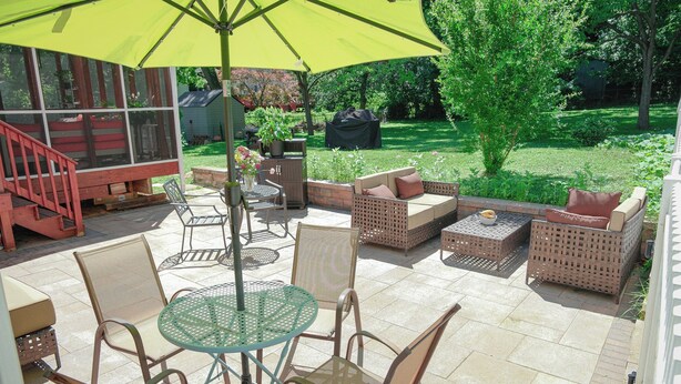 A patio area with outdoor furniture, including a table and chairs, under a large umbrella.