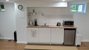 A compact kitchen with white cabinets, a wooden countertop, a built-in microwave, and a coffee maker.