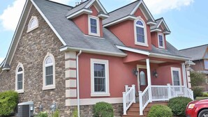 A two-story house with a stone facade, a red exterior, and a front porch with white railings. - Lovely Cottage W/ Jacuzzi & Fireplace (Millersburg)