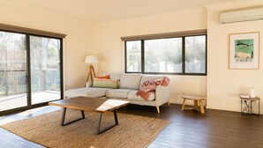 A modern living room with a sectional sofa, a coffee table, and large windows offering a view of the outdoors.