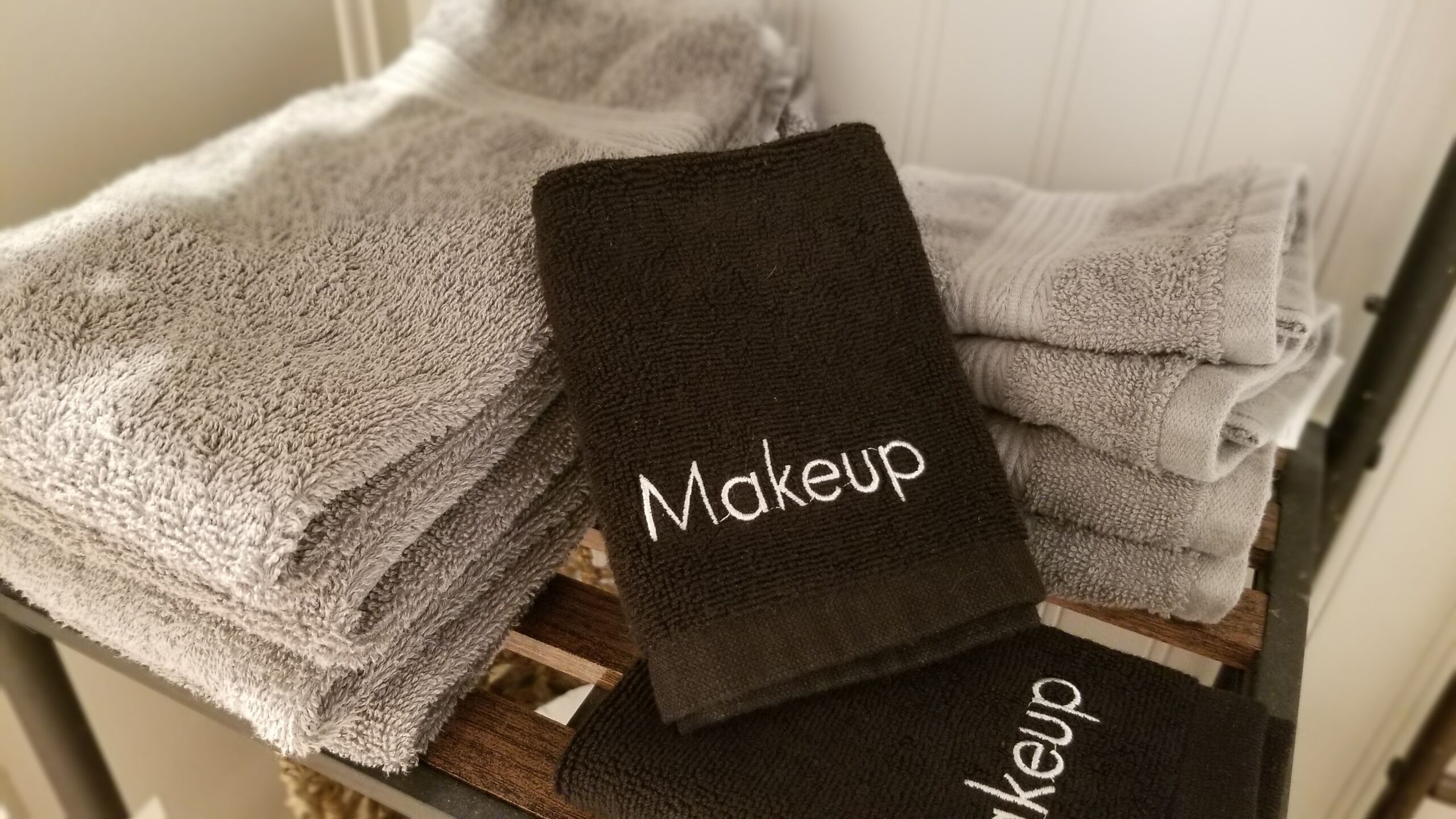 Una pila de toallas, una con la etiqueta 'Makeup' sobre una superficie de madera.