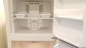 Un refrigerador blanco con varios estantes y compartimentos, incluyendo una sección congeladora a la derecha.