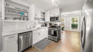 Une cuisine moderne avec des meubles blancs, des appareils en acier inoxydable et une vue sur l’extérieur.