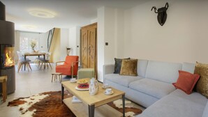 A living room with a sofa, a coffee table, a dining table with chairs, a fireplace, and a cowhide rug. - Chalet Ysopi - modern ski base for 9 La Clusaz - OVO Network (Saint-Jean-de-Sixt)