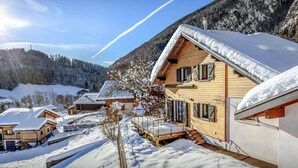 A wooden chalet with a steep roof, surrounded by snow-covered trees and mountains. - Chalet Ysopi - modern ski base for 9 La Clusaz - OVO Network (Saint-Jean-de-Sixt)