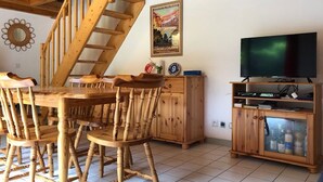 Una mesa de comedor de madera con sillas, un televisor y una escalera.