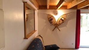 Una habitación con techo de madera, pared espejada, sofá con cojines estampados y un adorno de pared.