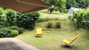 Un jardín con dos sillas amarillas y una sombrilla de patio.