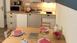 A compact kitchen with a wooden table set for four, equipped with a microwave, toaster, and kettle.