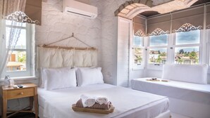 Een hotelkamer met een bed, nachtkastje, raam met uitzicht en een airconditioning.