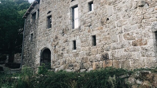 Ein Gebäude aus Stein mit mehreren Fenstern und einem sichtbaren Bogenportal.