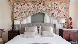A bedroom with a large bed, a decorative tapestry above the bed, and a nightstand with a lamp. - Casa de Piña, 700 mts to Newport Beach, headland views, spacious 2 bedrm apt.  (Newport)