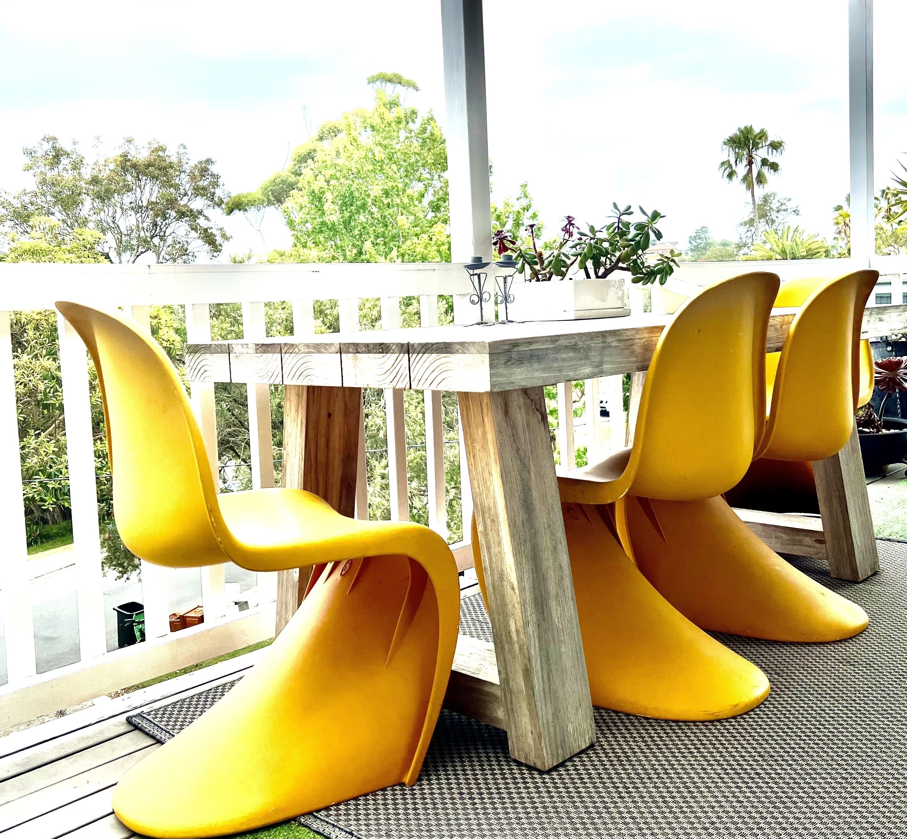 A wooden table with yellow chairs in a covered outdoor area.
