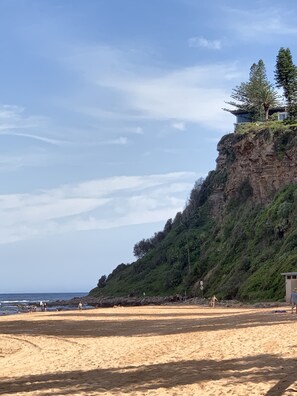 A beach with a rocky cliff and a building on top. - Casa de Piña, 700 mts to Newport Beach, headland views, spacious 2 bedrm apt.  (Newport)