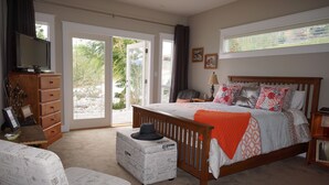 A bedroom with a bed, a dresser, a television, and a window with curtains. - Dreams B&B (Summerland)