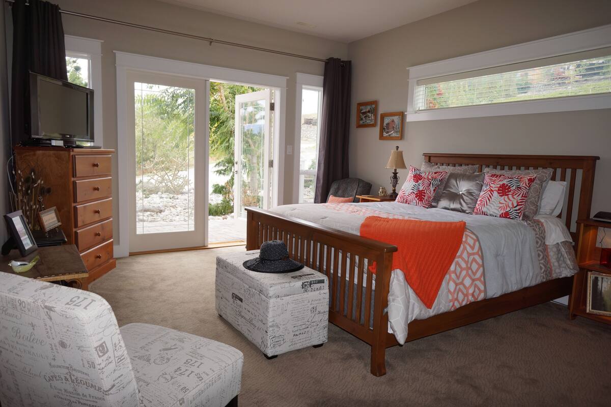 Un dormitorio con cama, cómoda, televisor y ventana con cortinas.