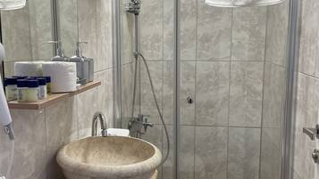 Ein modernes Badezimmer mit Marmorwaschtisch, einer Duschkabine aus Glas und einer Toilette.