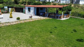 A small building with a red-tiled roof, a covered outdoor seating area, and a grassy lawn. - Parli Hotel (Gökçeada)