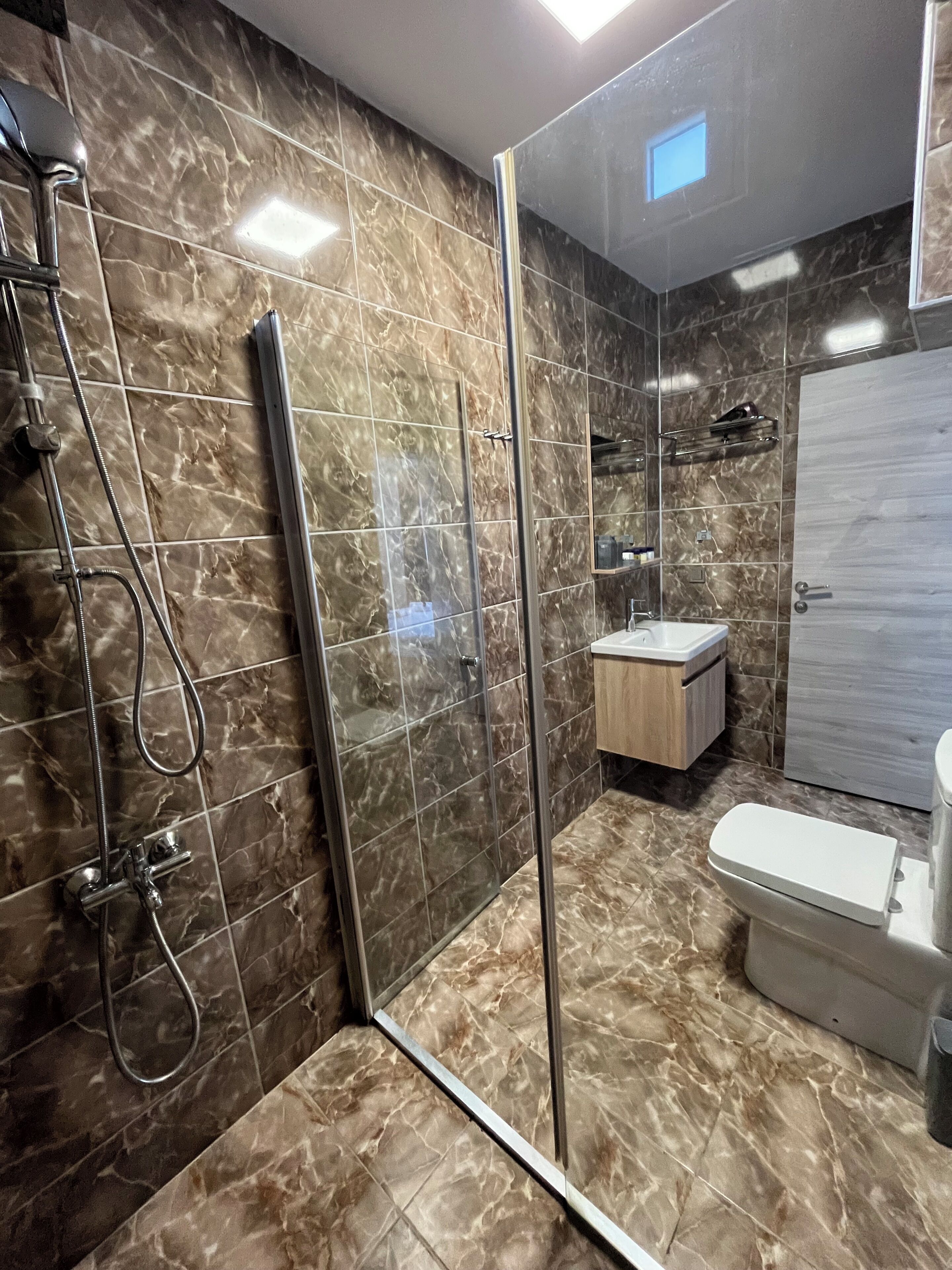 Ein modernes Badezimmer mit Duschkabine aus Glas, Toilette und Waschtisch mit Spiegel.