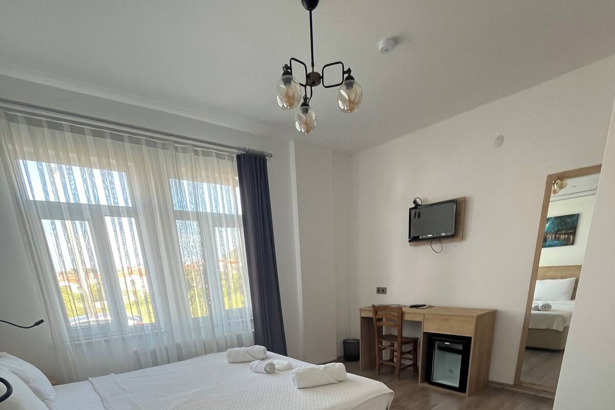 A hotel room with a bed, a desk, a chair, a television, and a mirror.