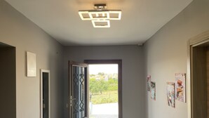 A hallway with patterned floor tiles, a fire extinguisher, a door with a decorative glass panel, and a ceiling light fixture. - Parli Hotel (Gökçeada)