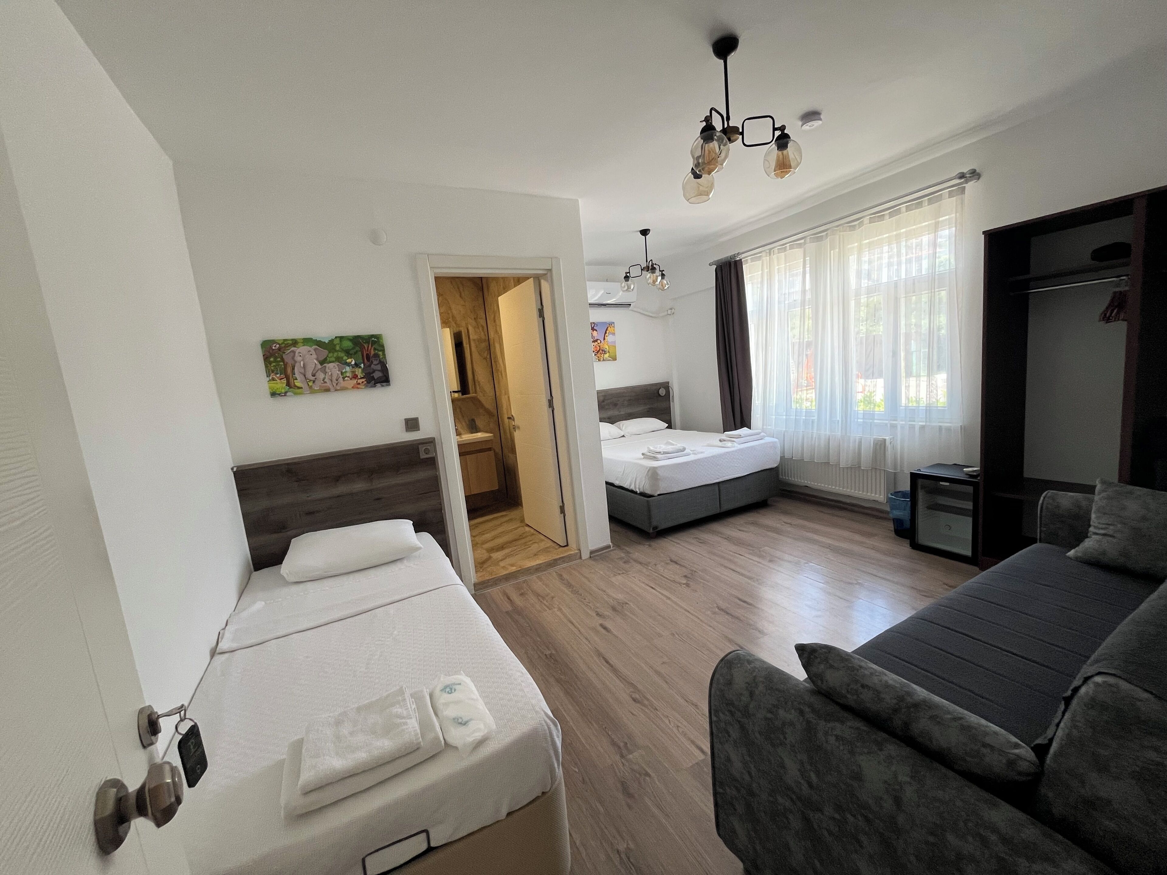 Una habitación de hotel con cama, sofá, baño y vistas al exterior.