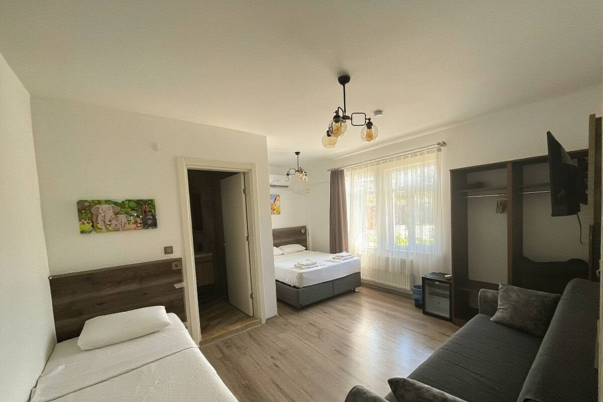 A room with a bed, a sofa, a desk, and a window with curtains.