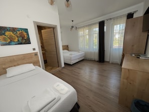 A bedroom with a bed, a wooden headboard, a painting, a wardrobe, and a desk.